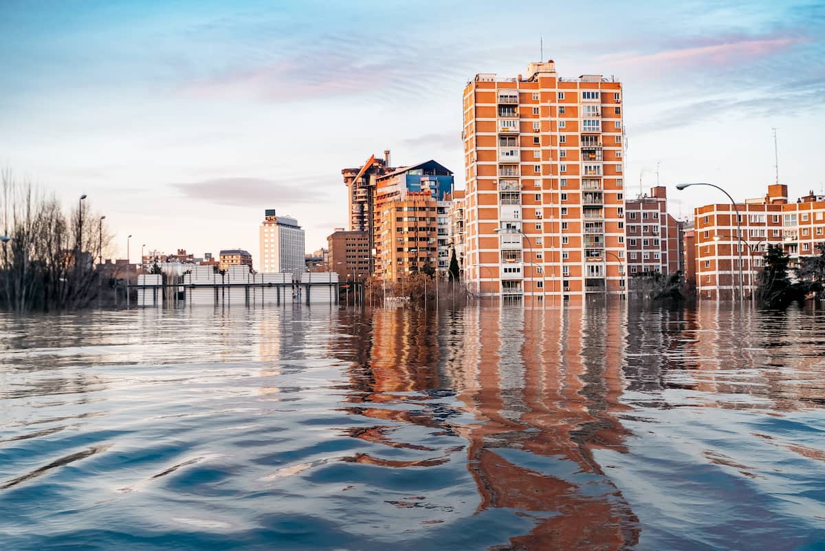 High-rise buildings reflecting on calm water during sunset.