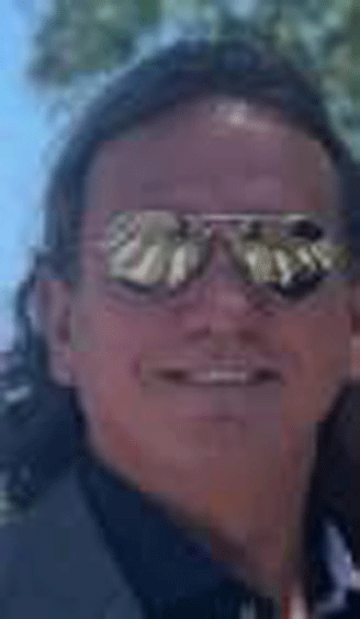 A man wearing reflective sunglasses and smiling.