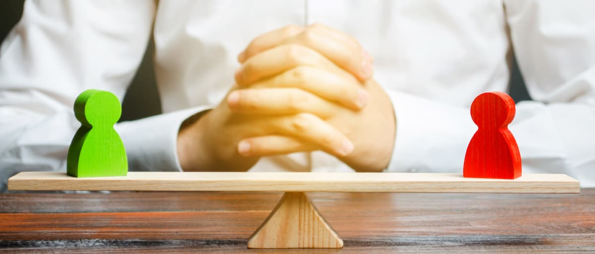 Hands clasped together resting on a wooden surface.