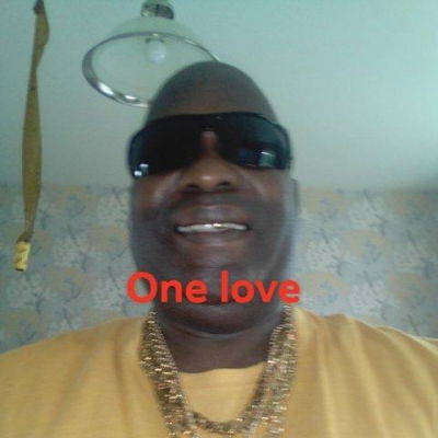 Man smiling with sunglasses and gold chains.