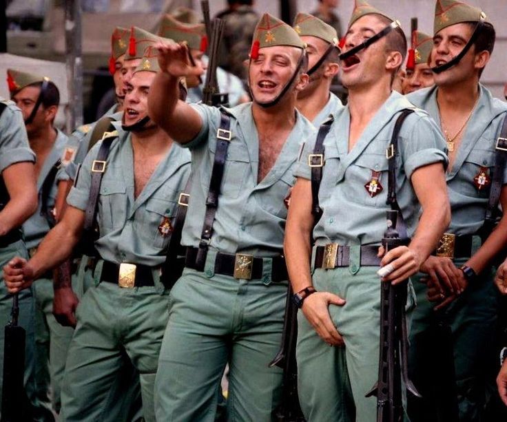 Soldiers in uniform laughing and gesturing energetically.