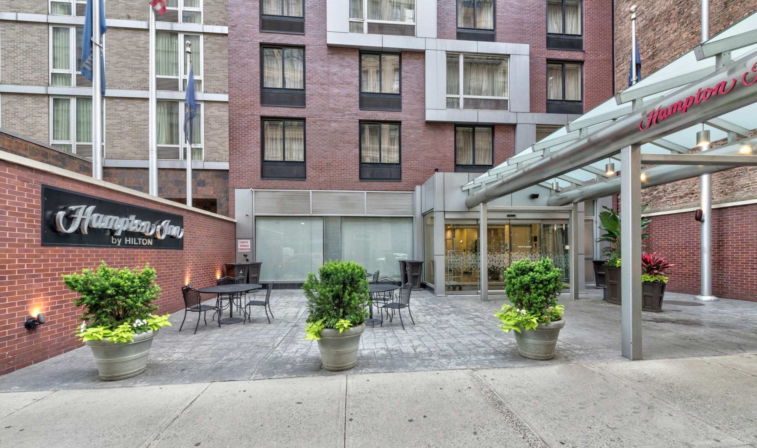 Hotel entrance with potted plants and sign.