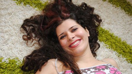 Smiling woman lying on patterned carpet.