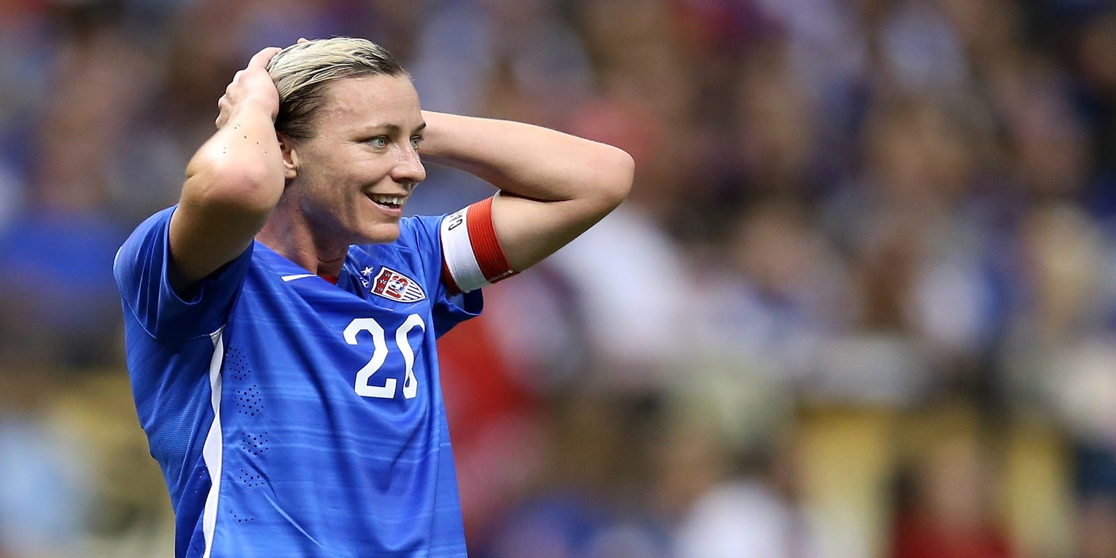 Soccer player smiling with hands on head.