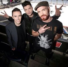 Three men posing and making peace signs.