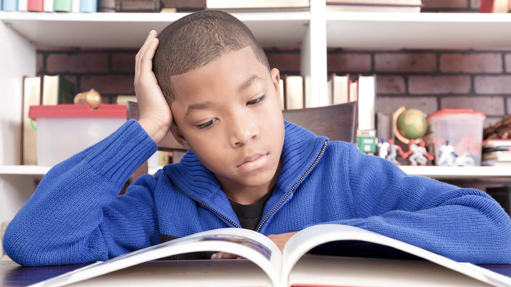 Boy reading a book at home.