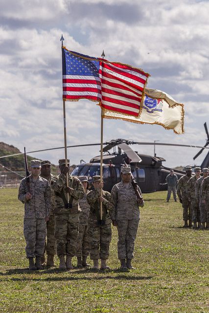 Soldiers holding flags in a field ceremony.