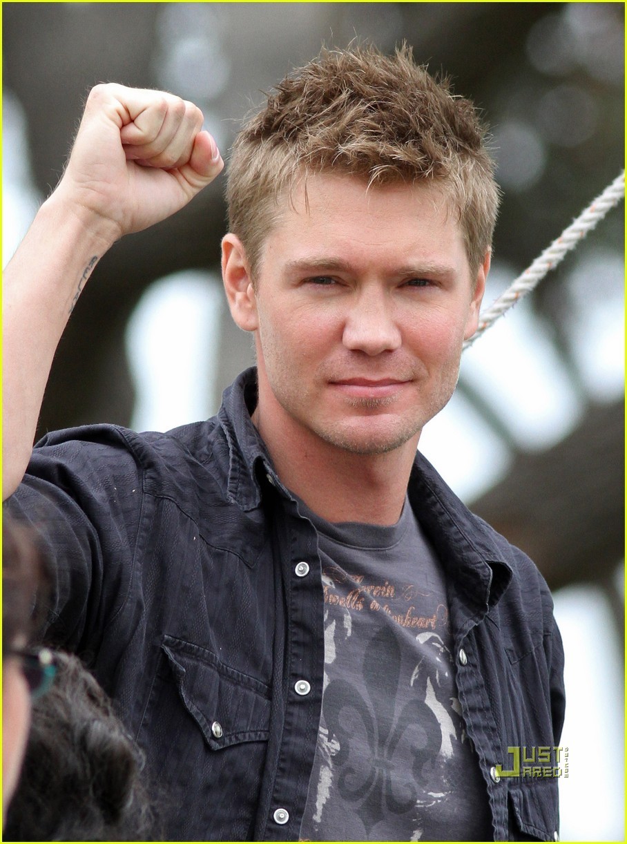 Man raising fist in casual attire outdoors.
