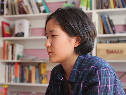 Person sitting in front of bookshelves.