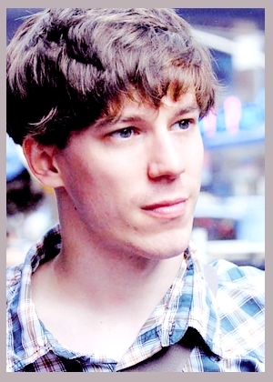 Young man in plaid shirt looking away.