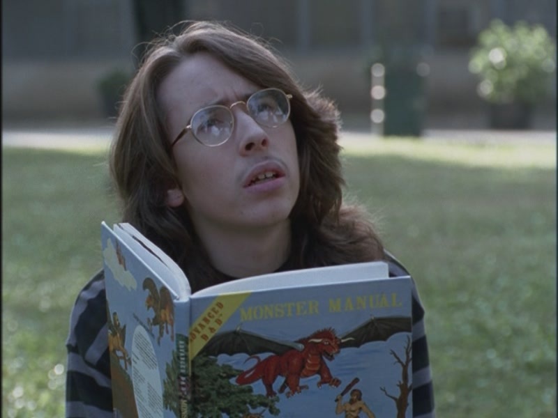 Person reading "Monster Manual" book outdoors.
