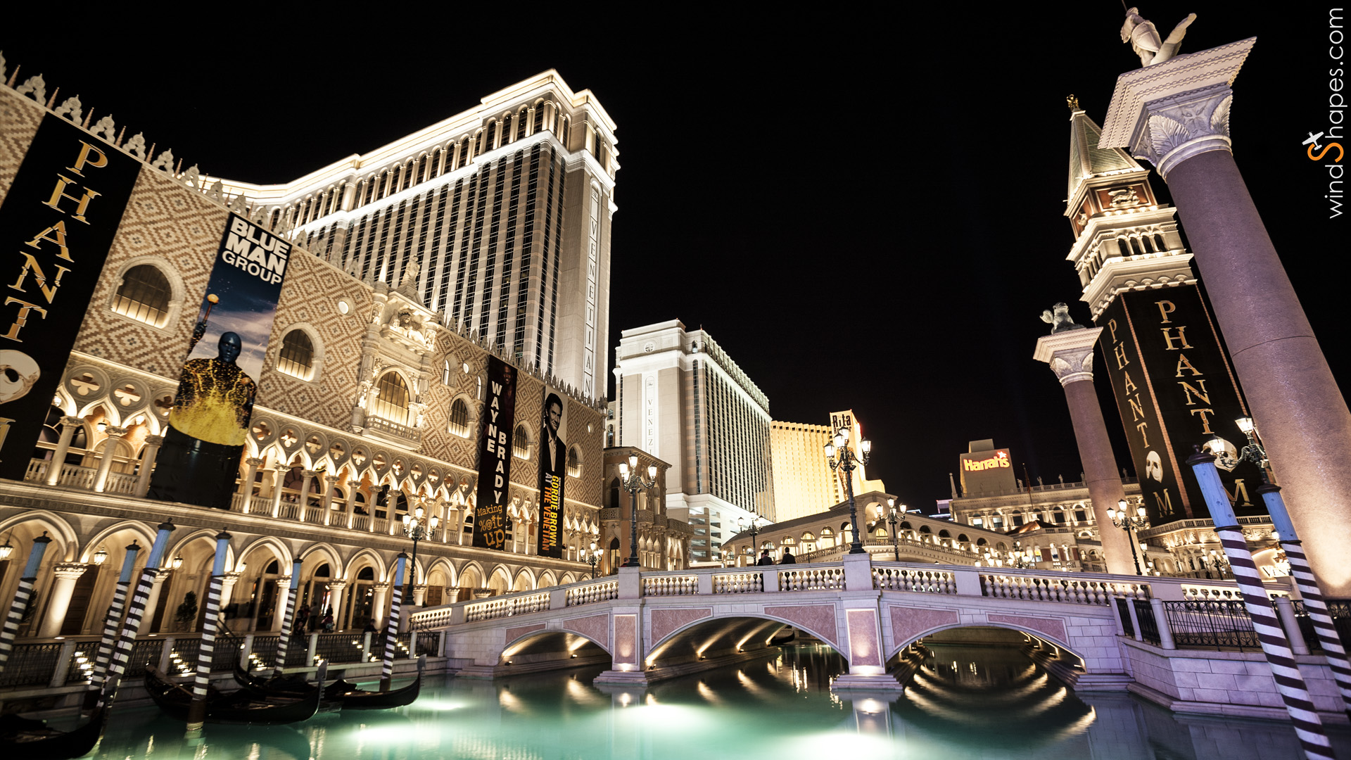 Venetian hotel exterior with illuminated bridge.