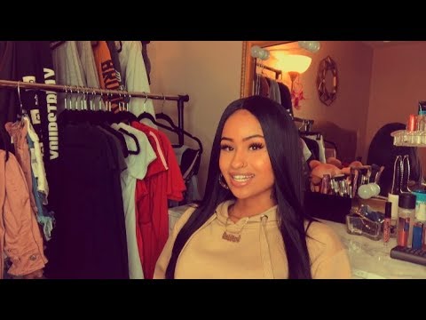 Smiling person in a bedroom with clothes.