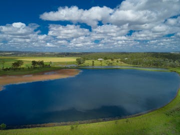 Lake with cloudy sky and surrounding fields.