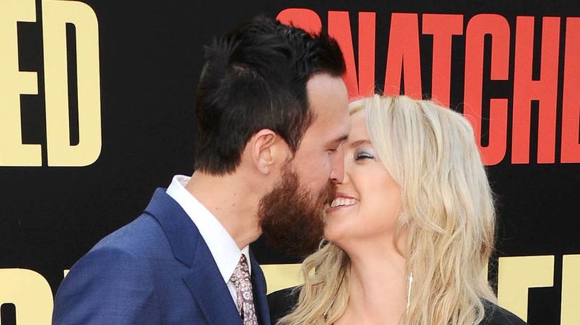 Couple smiling and embracing at movie premiere.