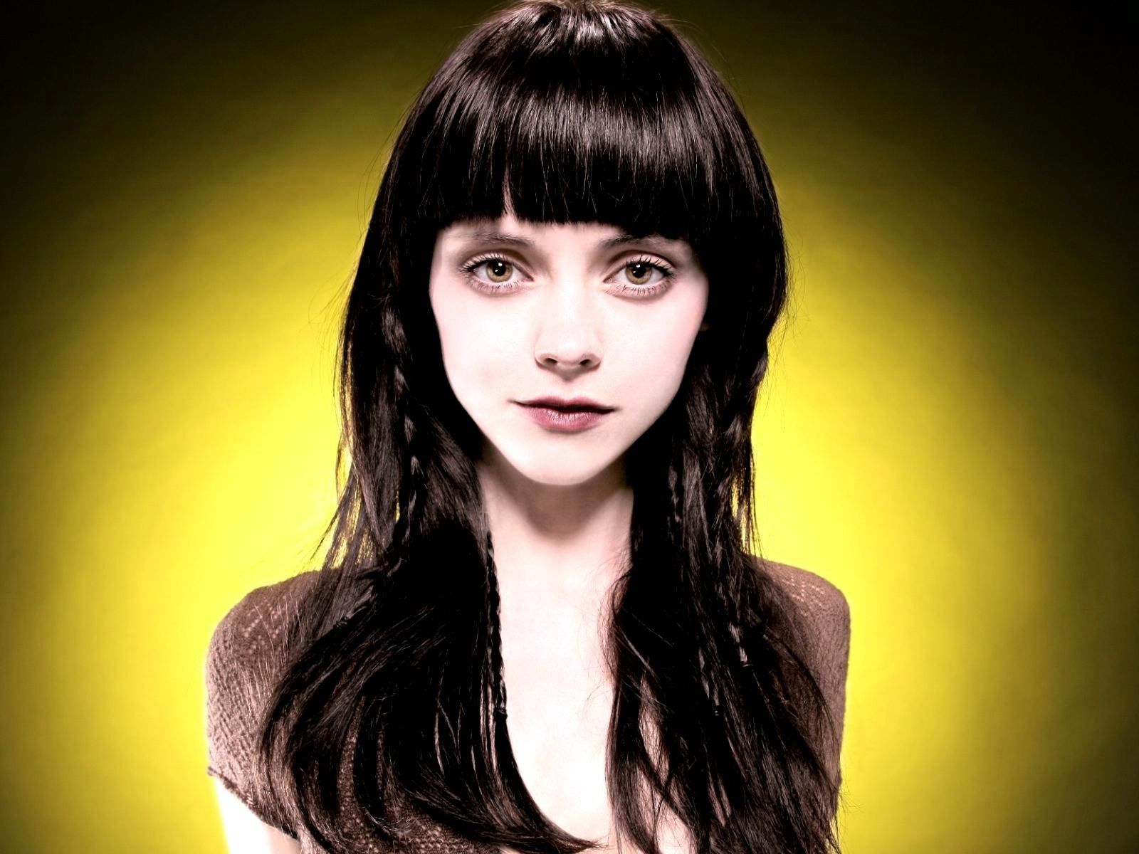 Woman with long dark hair, yellow background.
