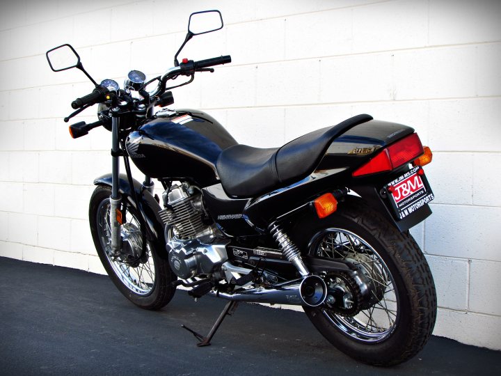 Black motorcycle parked near a white wall.