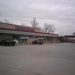 Storefront with parked vehicles on cloudy day.
