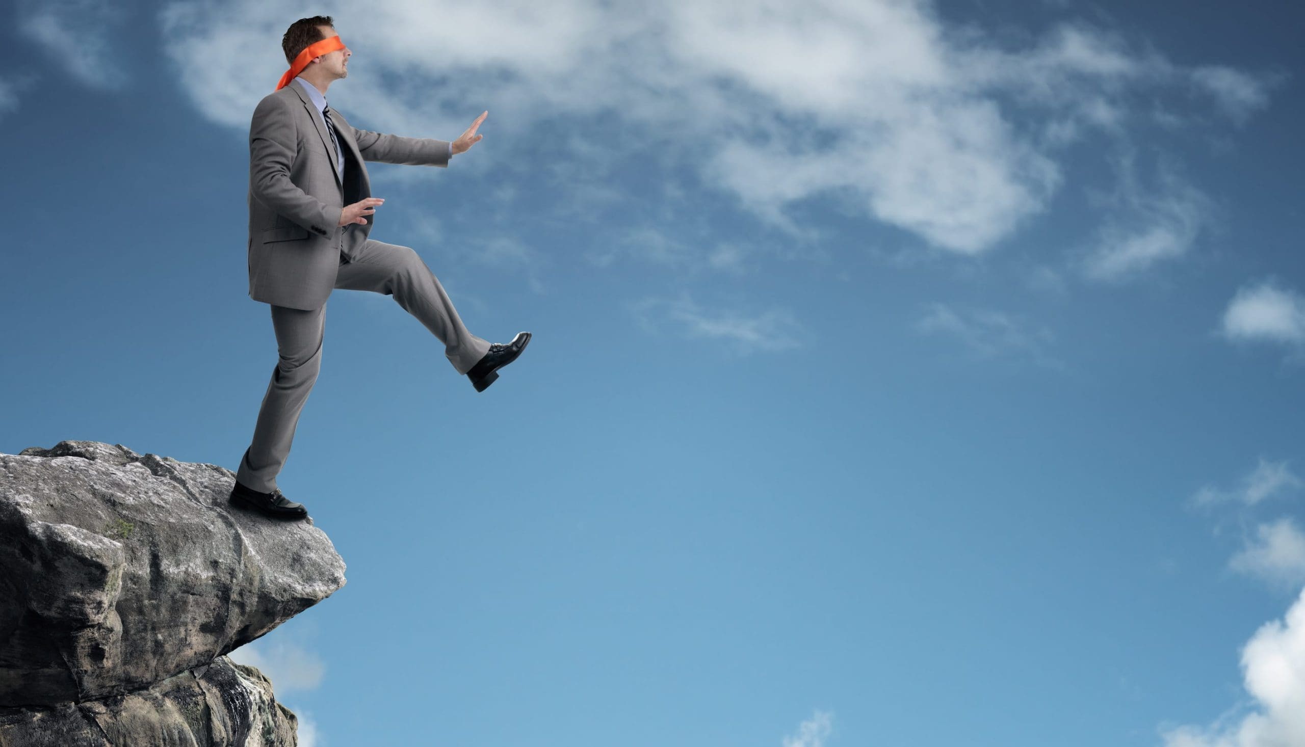 Blindfolded man stepping off cliff edge.