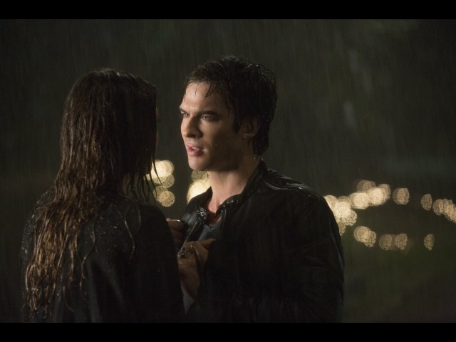 Couple standing in rain at night.